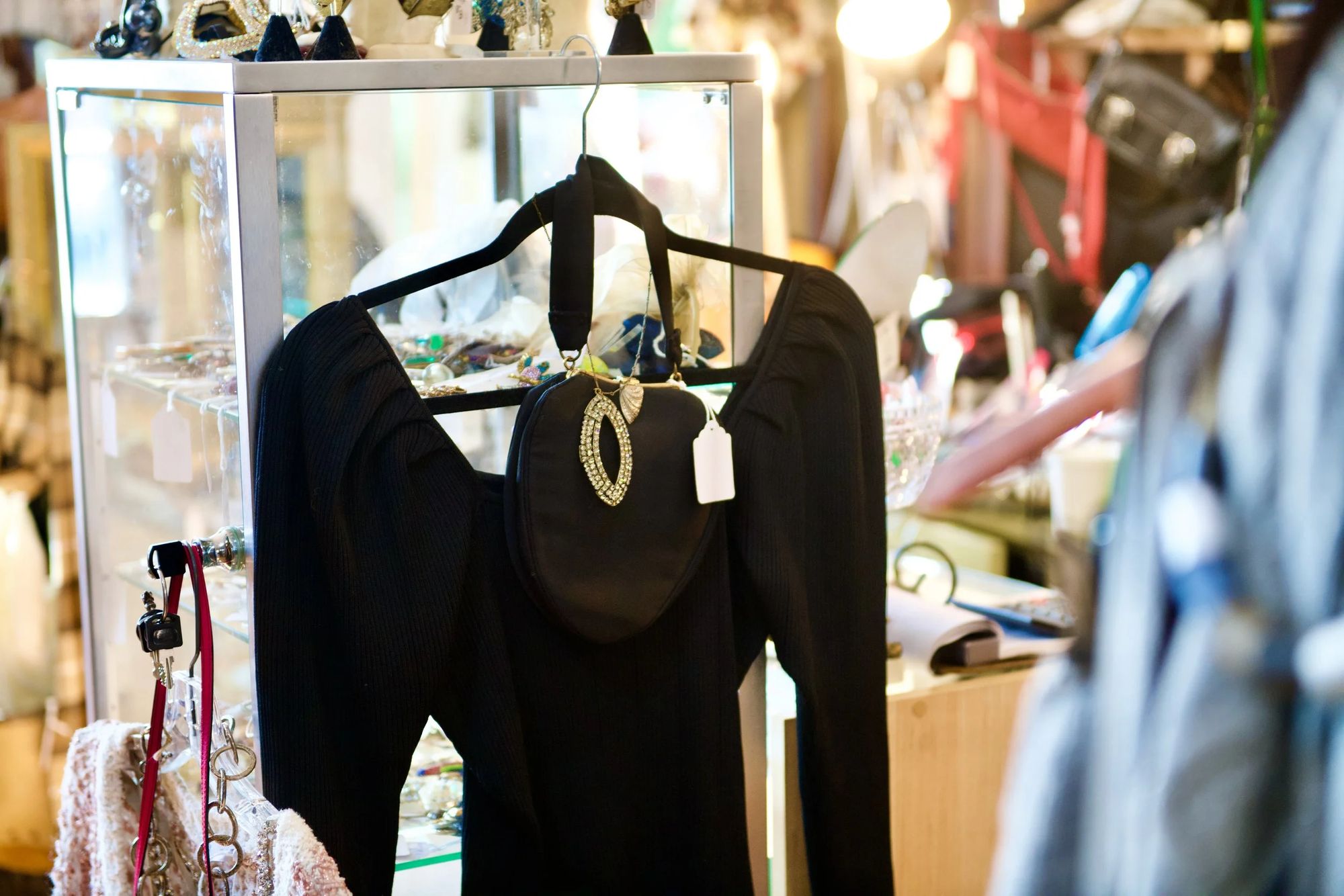 A black ribbed dress with a rhinestone-clasp evening bag, in front of the jewelry case